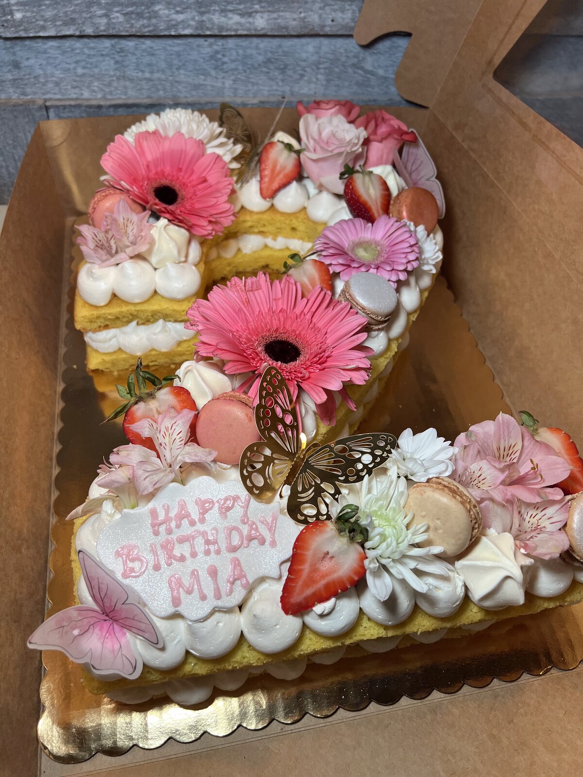 Heart-shaped custom celebration cake with floral piping, strawberries, and macarons at Lu's
