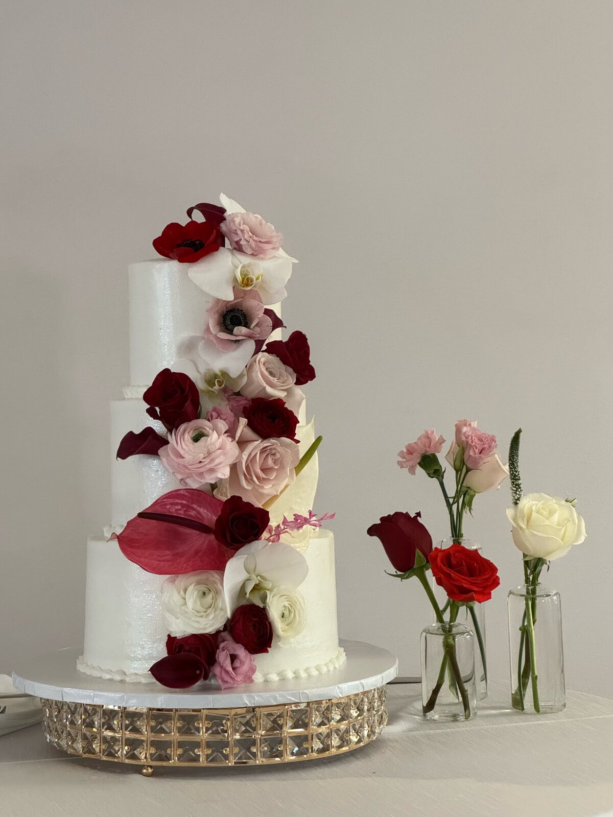 Tiered wedding cake with burgundy and blush florals at Lu's